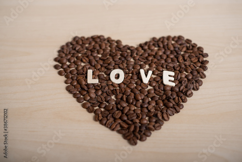 Coffee beans in the shape of a heart and the inscription love on a wooden table