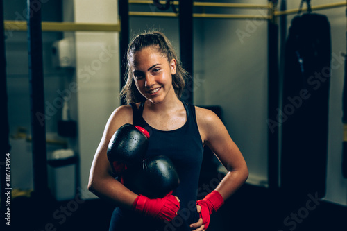 woman holding boxing gloves and posing in gym