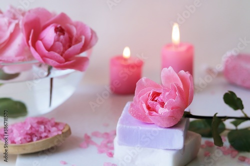 Fresh pink roses  water  petals  candles on a light background  body care products  natural home cosmetics  healthy lifestyle  alternative medicine