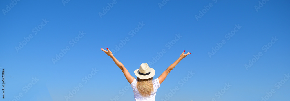 Woman in hat raised her hands against the blue sky Woman in hat raised her hands against the blue sky