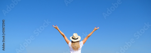 Woman in hat raised her hands against the blue sky