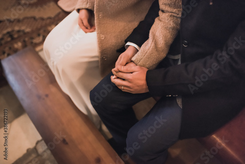 A couple of lovers are sitting on a bench next to each other holding hands. man holding woman s hands