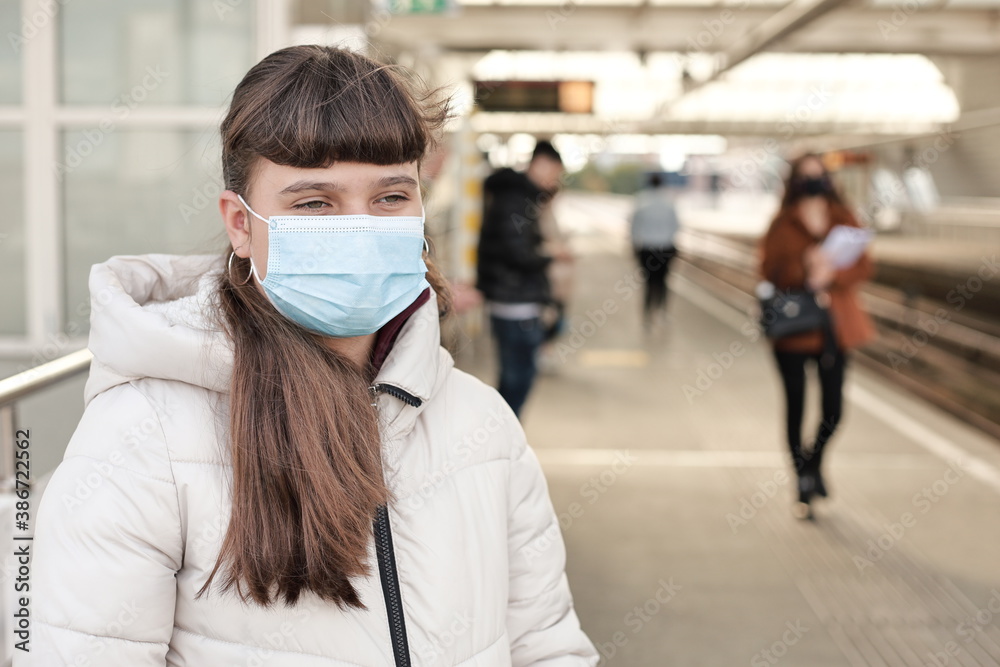 A person girl teenager wearing face mask standing on the metro station in Europe, Spijkenisse, the Netherlands. Stop coronavirus and transport