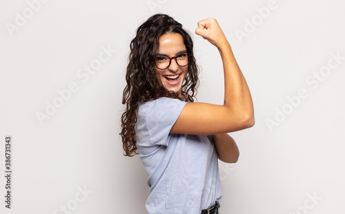 Foto pretty young woman feeling happy, satisfied and powerful, flexing fit and muscul