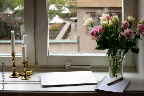 Ready for online dating by the window with roses and laptop