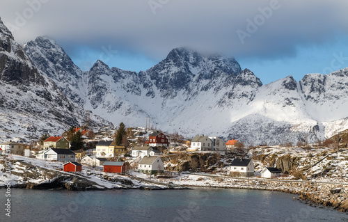 Lofoten islands, Norway. Authentic fishing village by the fjord at the foot of the mountains in winter at golden hour.