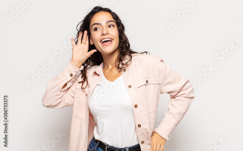 pretty young woman smiling, looking curiously to the side, trying to listen to gossip or overhearing a secret photo