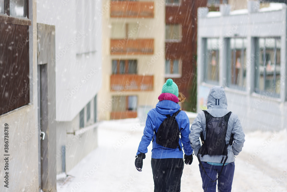 Tourists walking on street of mountain resort town in Switzerland, Europe. Winter vacation. Ski resort.