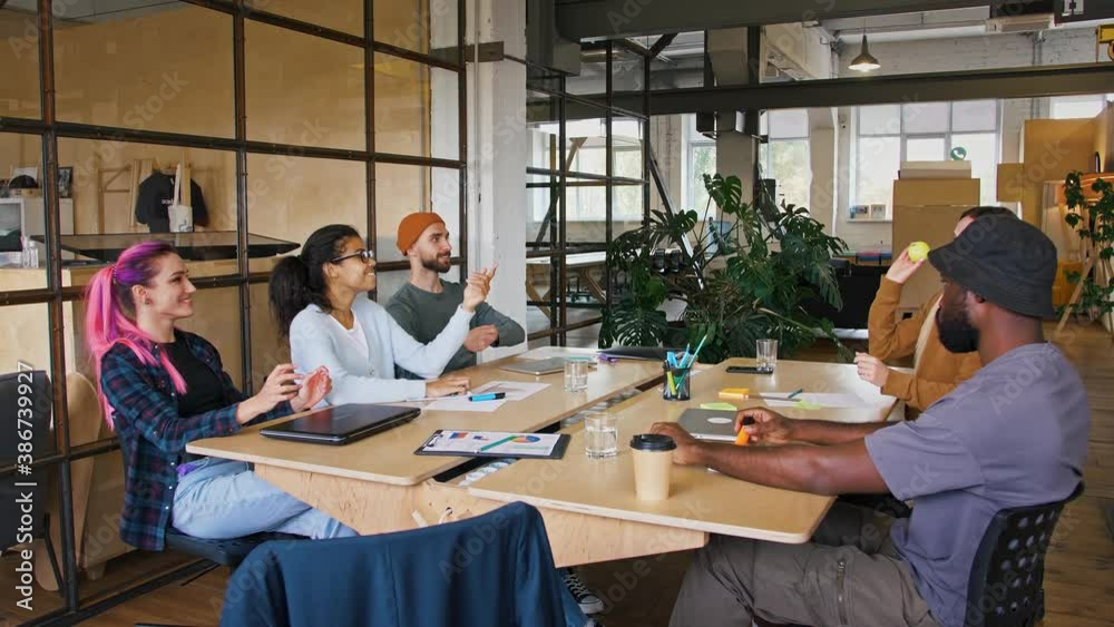 Multiethnic group plays with tennis ball, sitting at desk in modern office, tracking shot Multiethnic group plays with tennis ball, sitting at desk in modern office, tracking shot