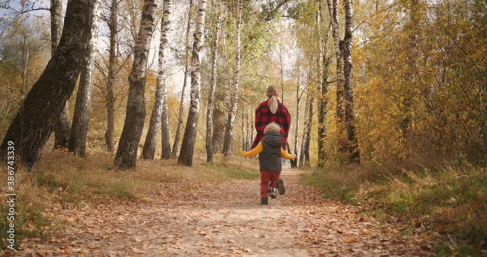 happy woman and little boy are resting in forest at autumn, son is running to mother and she is lifting him on hands and whirling, joyful family happy woman and little boy are resting in forest at autumn, son is running to mother and she is lifting him on hands and whirling, joyful family