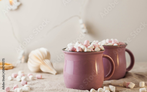 Hot chocolate with marshmallows in mugs on a linen tablecloth with Christmas toy. concept of winter home away from home