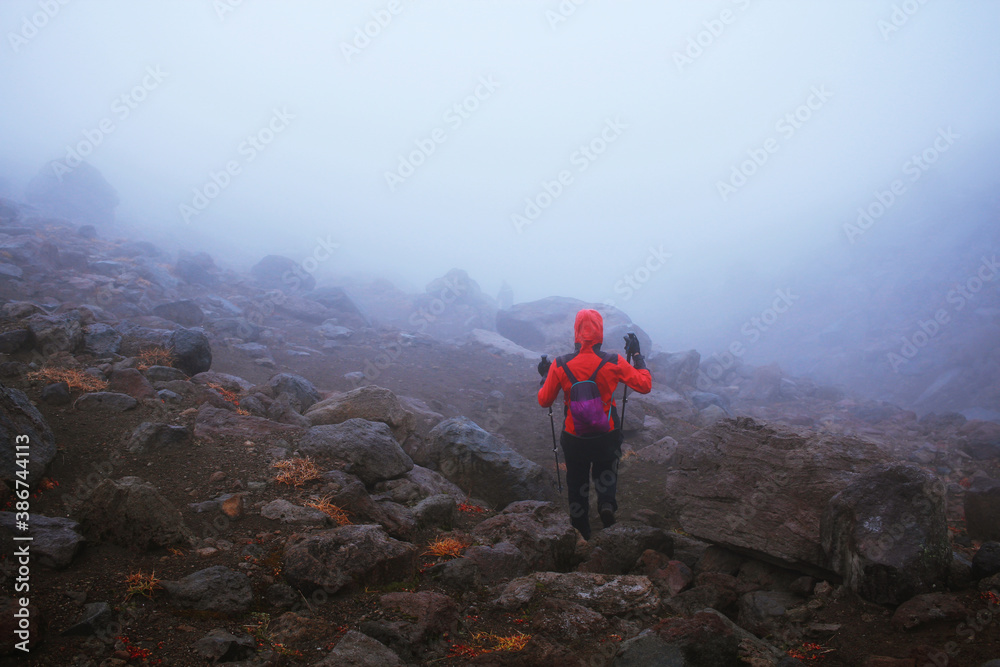 Obraz premium The tourist overcomes a difficult transition. Hiking in bad weather, through rain and fog. Active outdoors people lifestyle