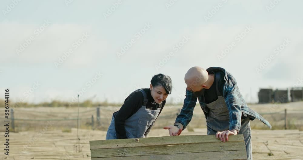 Farmer explaining the breeding of snails to a young woman in dungarees on a windy day on a snail farm. Portrait of a handsome farmer standing in front of the hothouse farm with snail breeding Farmer explaining the breeding of snails to a young woman in dungarees on a windy day on a snail farm. Portrait of a handsome farmer standing in front of the hothouse farm with snail breeding