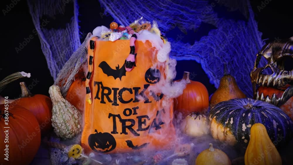 Halloween bag full of candies and sweets. Trick or treat, Halloween spooky scenery with pumpkins, misty fog, candies, skull, spiders and bats. 
