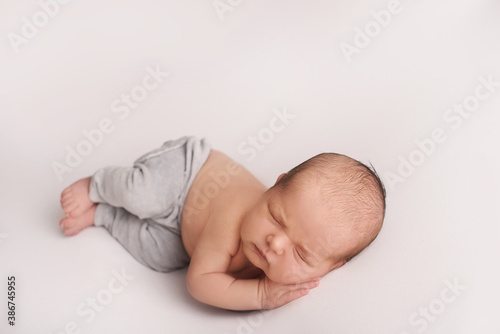 newborn photoshoot of a small newborn baby sleeps on his tummy, propping his cheek with his palm, a photo session of a newborn little baby