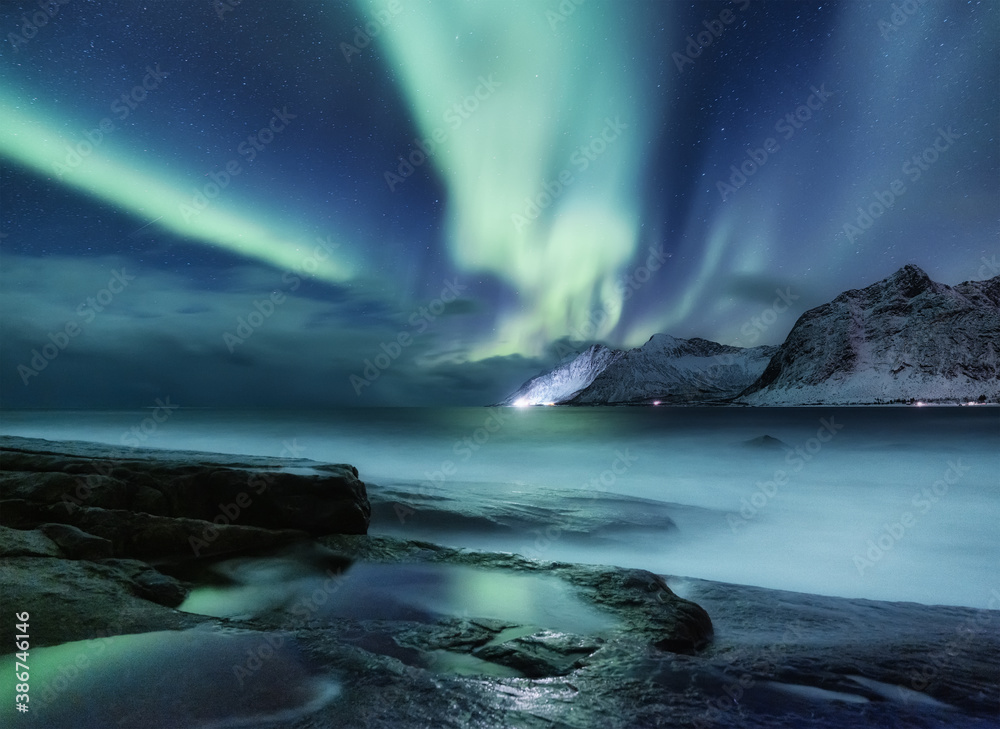 Aurora Borealis on Senja island, Norway. Northern lights above mountains and ocean. Night landscape with Aurora lights. North view