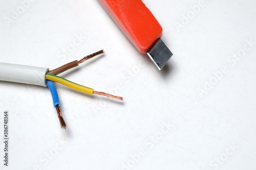 stripped three-wire, electric cable and stationery knife. on white background.