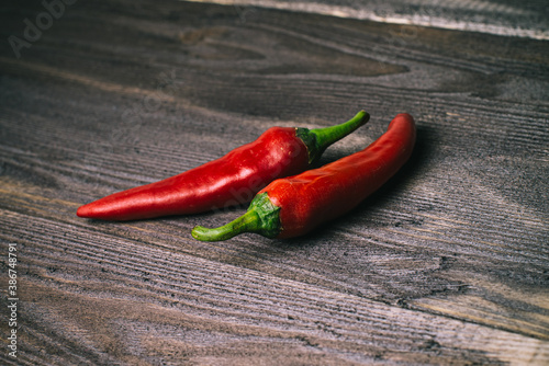 Two fresh chili peppers on a dark wood background, copyspace