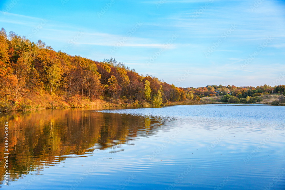 autumn landscape of lake and orange forest on the slope. panoramic view of the forest river on a sunny autumn day
