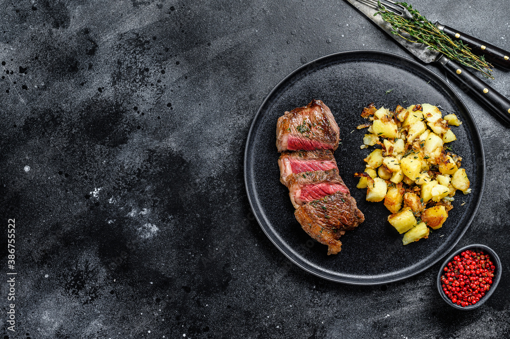 Grilled Striploin steak with potato, beef meat. Black background. Top view. Copy space