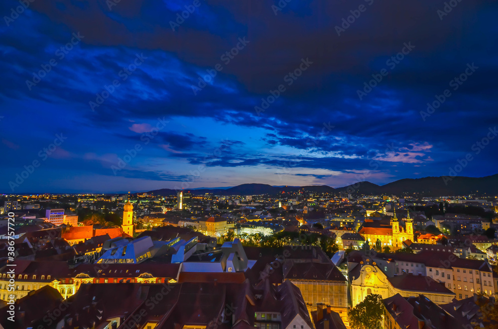 City lights of Graz and Mariahilfer church, view from the Schlossberg hill, in Graz, Styria region, Austria, after sunset. Dramatic sky, panoramic view.