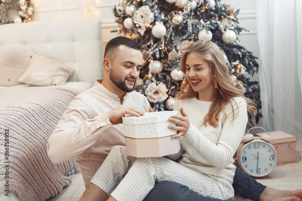 Couple near christmas tree. Lady in a pajamas. Man in a white shirt. Couple near christmas tree. Lady in a pajamas. Man in a white shirt.