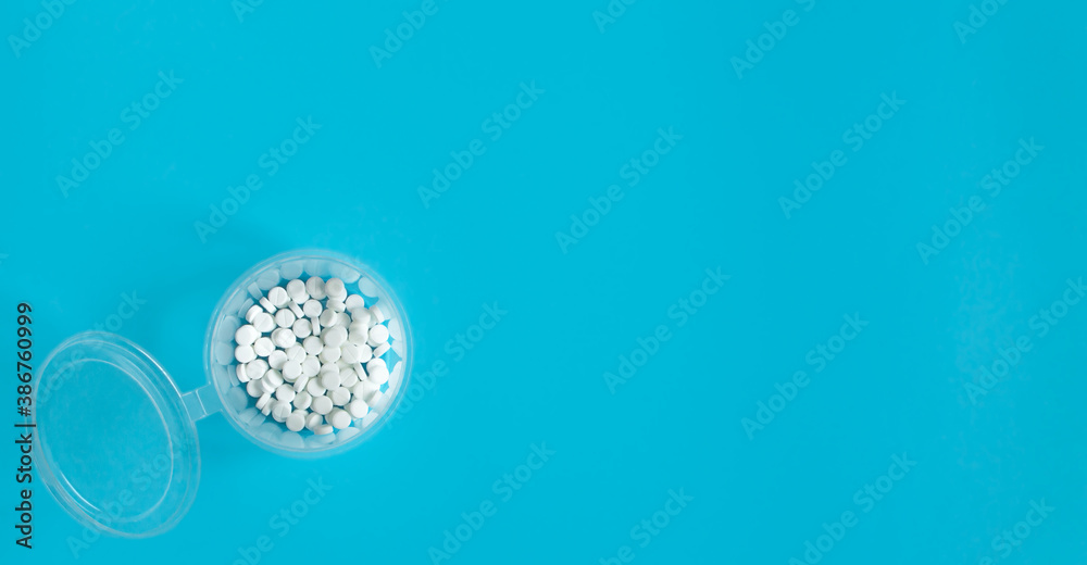 White tablets in container on a blue background