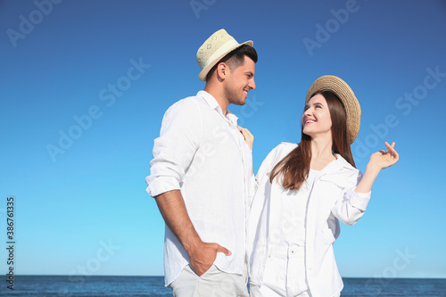 Lovely couple wearing hats together on beach