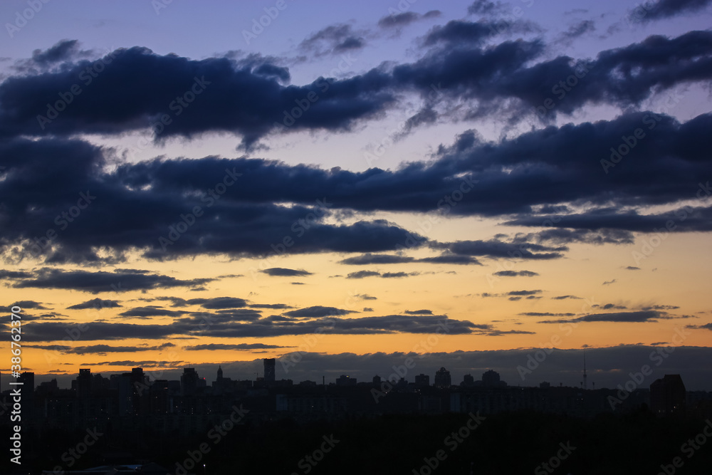 Fototapeta premium Beautiful sunset and clouds in the sunset orange and blue sky, big city view