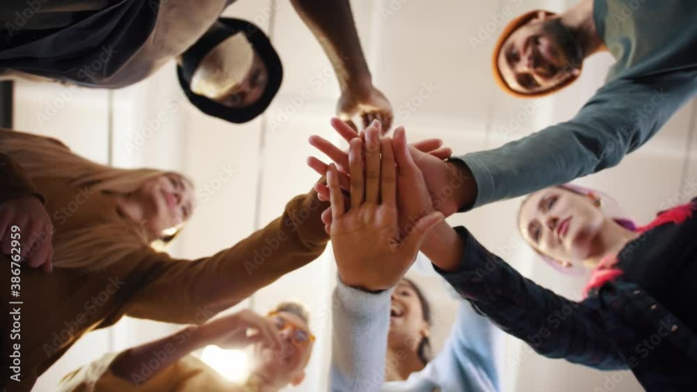 Multiethnic team putting hands together one by one, connection, teambuilding and alliance concept, below view