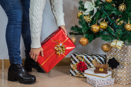 mujer dejando regalo de navidad debajo de árbol navideño photo