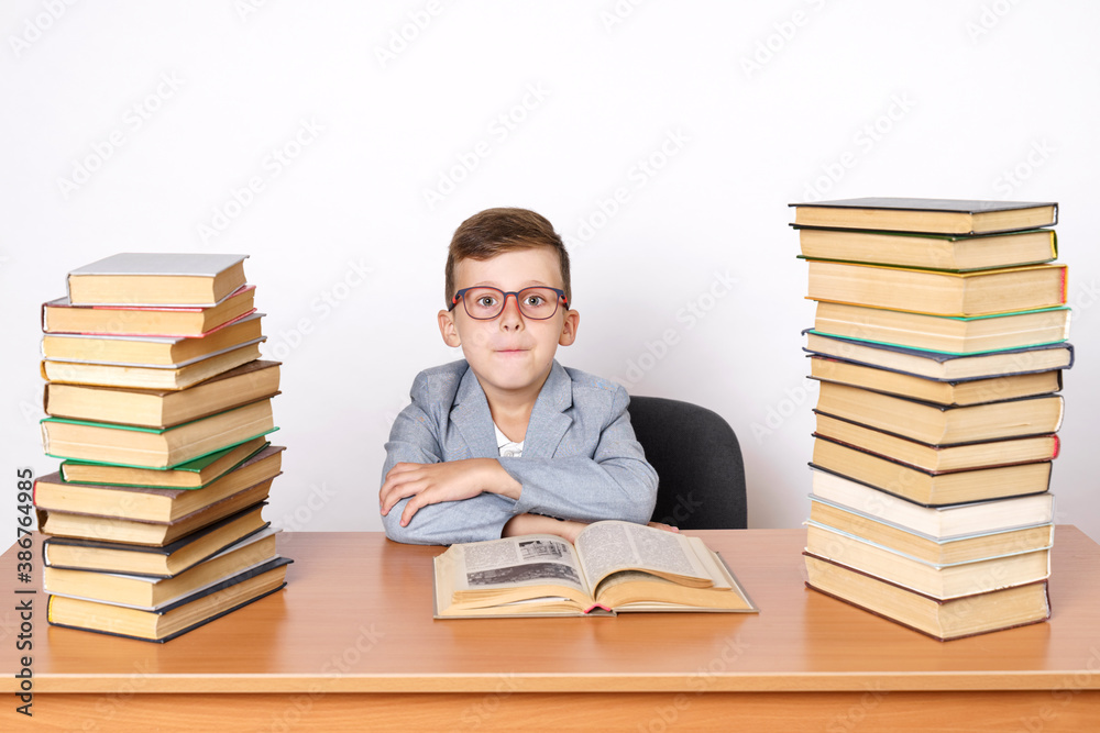 A student with glasses sits at a table with books on both sides. A student with glasses sits at a table with books on both sides.