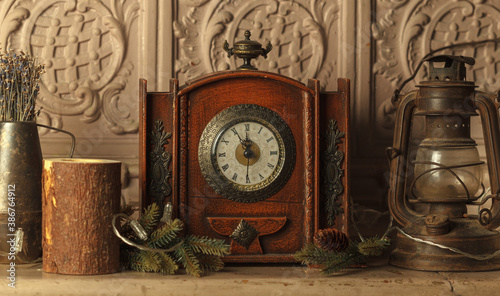 the antique clock on the mantelpiece shows five minutes to midnight. Close-up in a low key, with vintage interior items. The concept of the new year