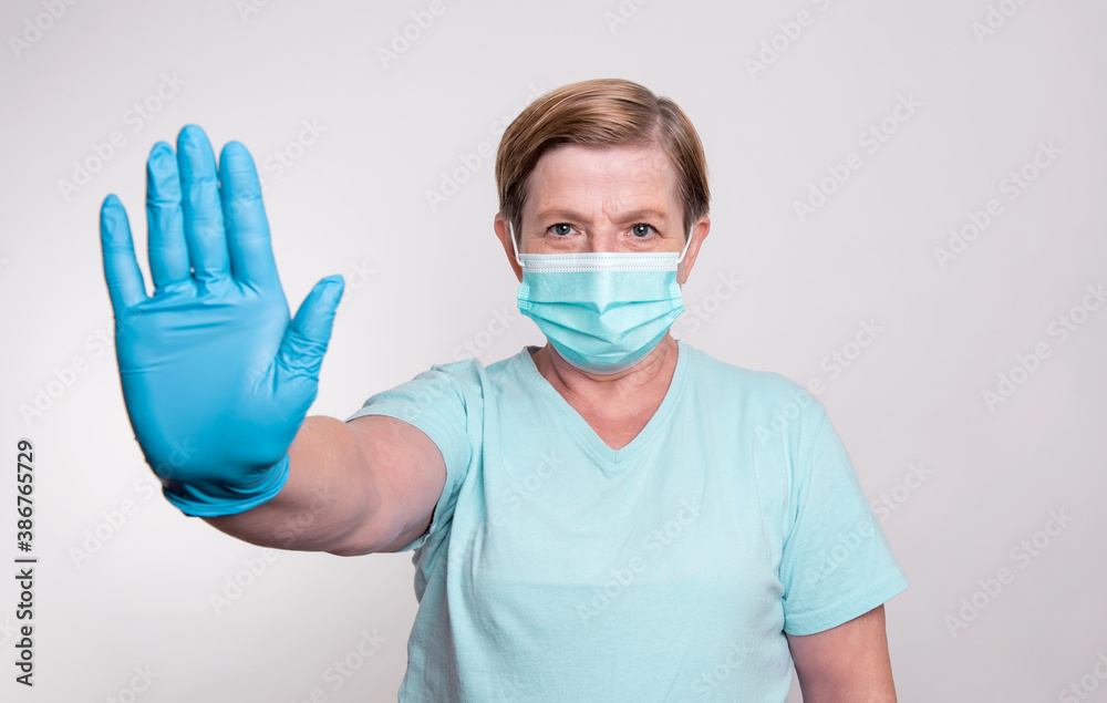 Elderly woman wearing gloves and putting on mask to stay safe and prevent spreading corona virus Elderly woman wearing gloves and putting on mask to stay safe and prevent spreading corona virus
