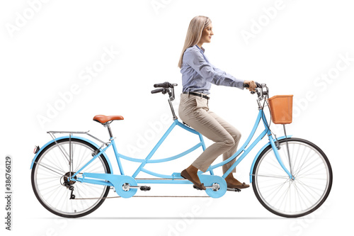 Young blond woman in formal clothes riding a tandem bicycle