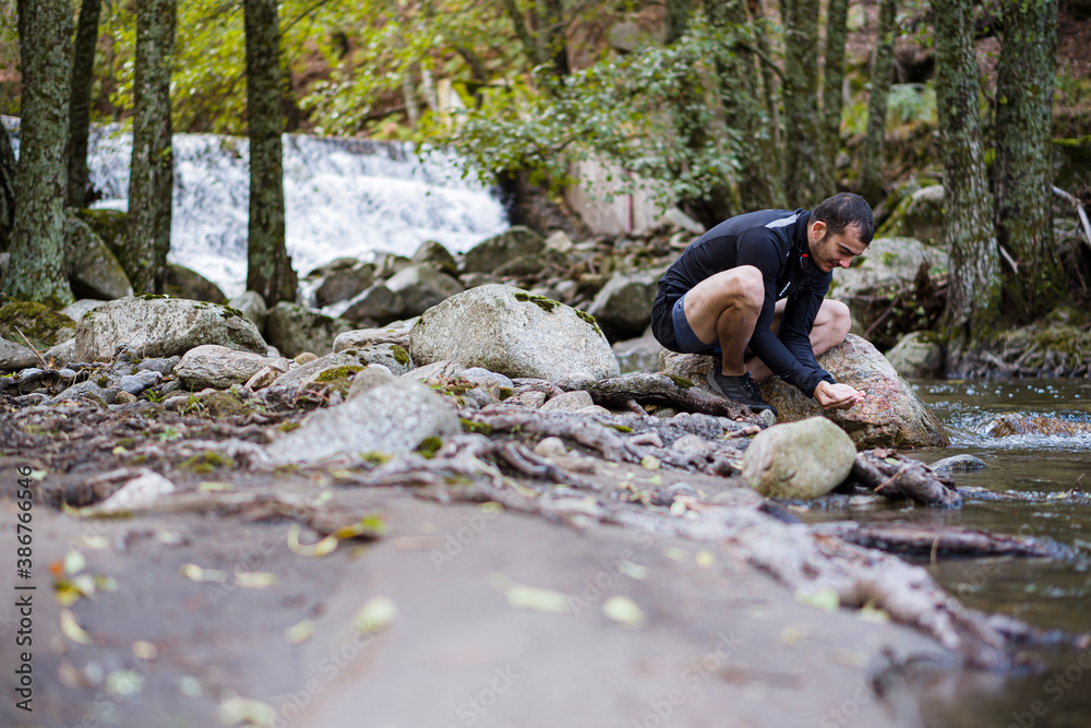 Hombre cogiendo agua de un rio natural en el bosque en una garganta de