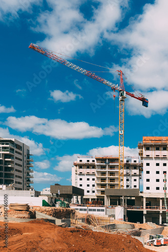 Construction site with cranes and sand on blue sky background. Modern building new houses for people. House building area in the city.