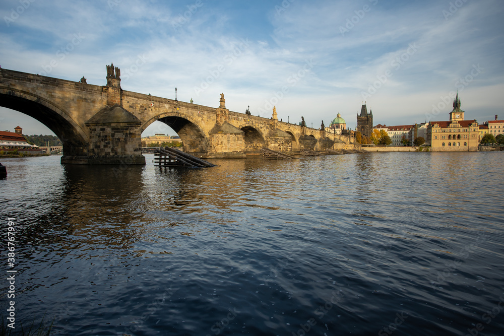 
the monument of Charles Bridge from 1402 and the level of the flowing Vltava river and the light from the sun at sunset in the center of Prague in the Czech Republic