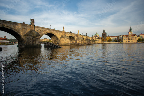  the monument of Charles Bridge from 1402 and the level of the flowing Vltava river and the light from the sun at sunset in the center of Prague in the Czech Republic