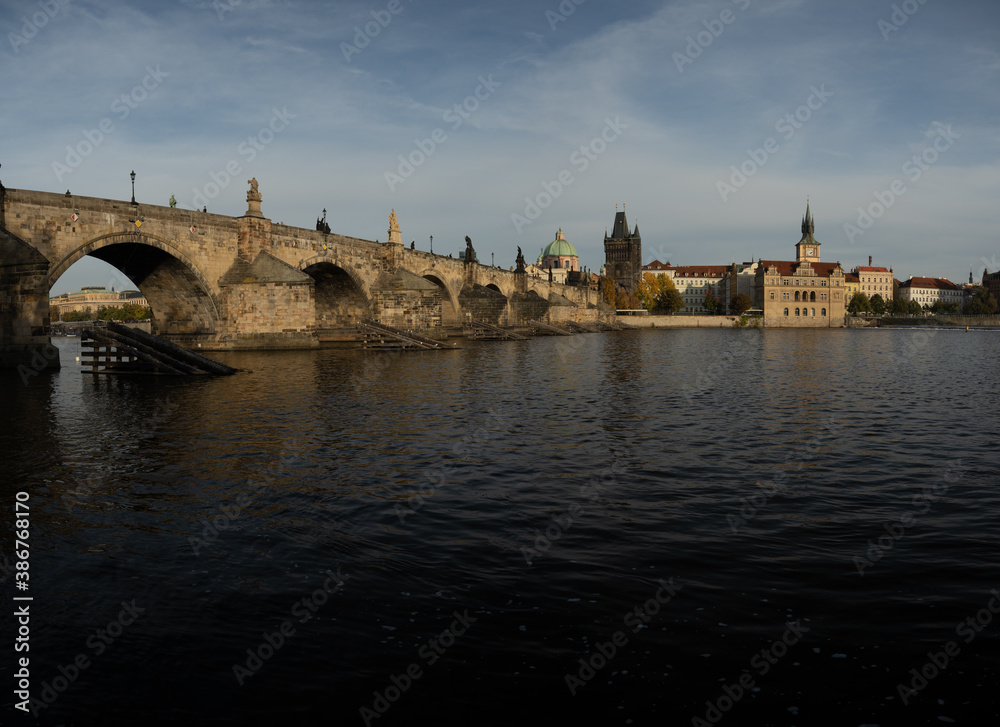 
the monument of Charles Bridge from 1402 and the level of the flowing Vltava river and the light from the sun at sunset in the center of Prague in the Czech Republic