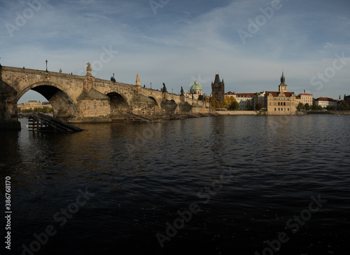  the monument of Charles Bridge from 1402 and the level of the flowing Vltava river and the light from the sun at sunset in the center of Prague in the Czech Republic