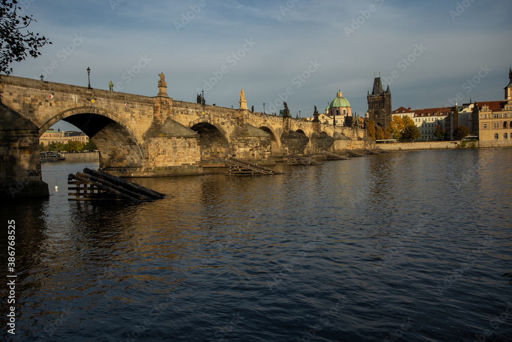 the monument of Charles Bridge from 1402 and the level of the flowing Vltava river and the light from the sun at sunset in the center of Prague in the Czech Republic