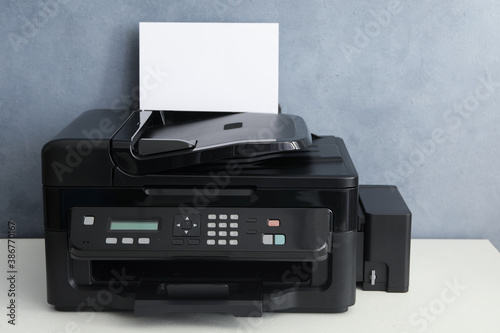 Modern printer with paper on white table