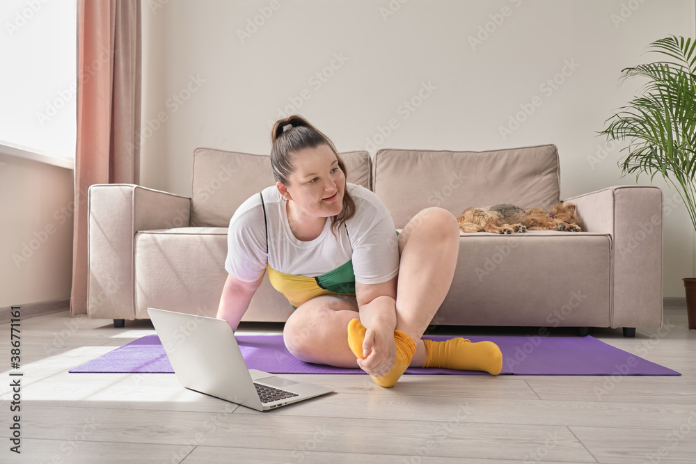 An overweight woman does sports at home online. A pet, a small dog, is sleeping on the sofa. An overweight woman does sports at home online. A pet, a small dog, is sleeping on the sofa.