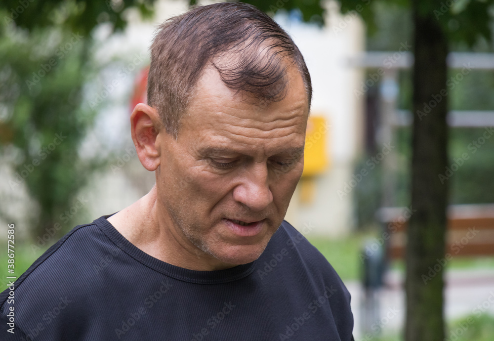Close-up portrait of a sixty-year-old man with his head down and looking sad. Close-up portrait of a sixty-year-old man with his head down and looking sad.