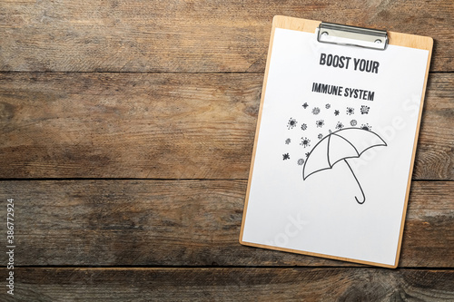 Clipboard with phrase Boost Your Immune System on wooden table, top view. Space for text photo