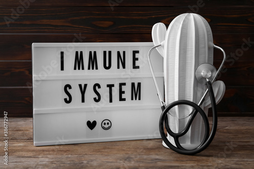 Lightbox with phrase Immune System, ceramic cactus and stethoscope on wooden table photo