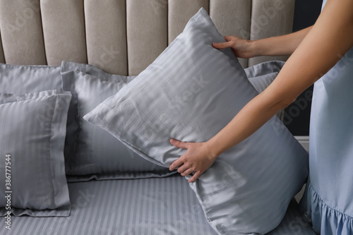 Woman putting soft pillow on bed  closeup