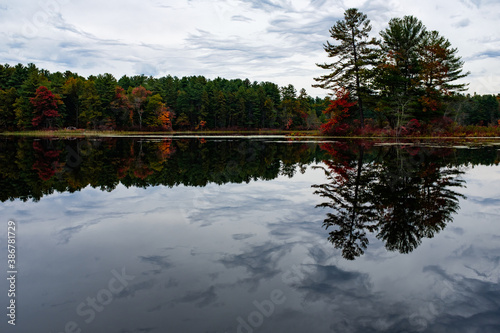 Fall trees and sky reflecting in a New England lake photo