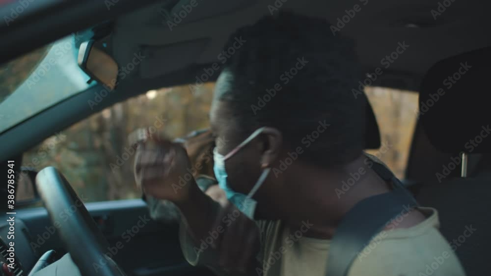 Creepy zombie man attacking african guy driving car on road